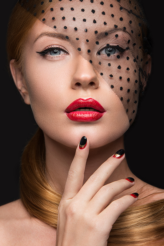 Beautiful girl with a veil, evening makeup, black and red nails. Design manicure. Beauty face. Picture taken in the studio.